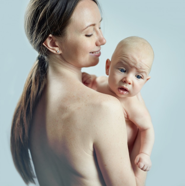 Foto mulher com um bebê nos braços em um fundo de parede azul