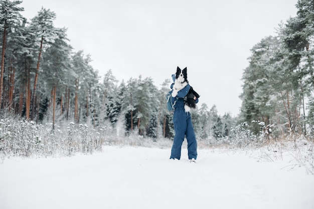 Mulher com um cachorro border collie na floresta de neve