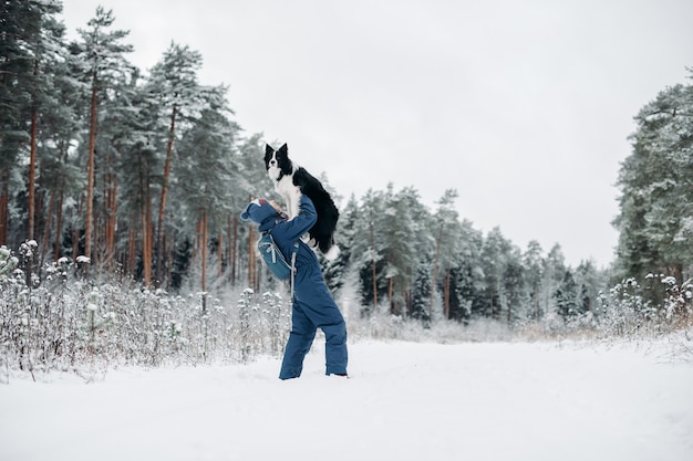 Mulher com um cachorro border collie na floresta de neve