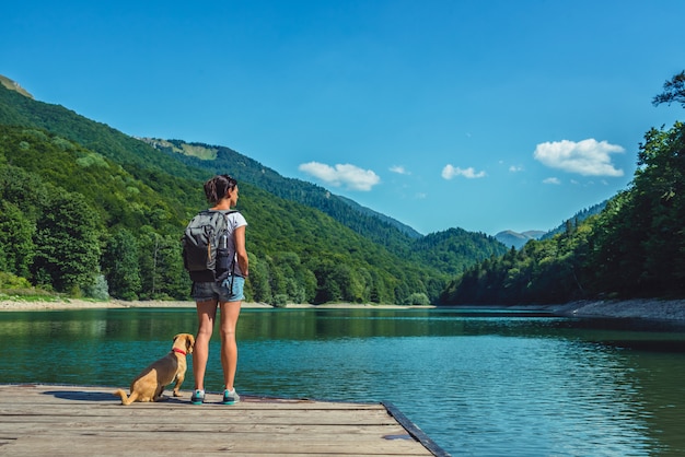 Mulher com um cachorro em pé em um píer