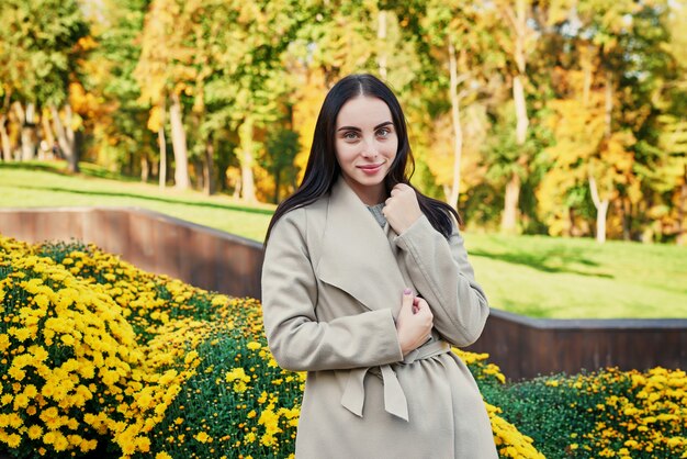 mulher com um casaco bege caminha no parque outono