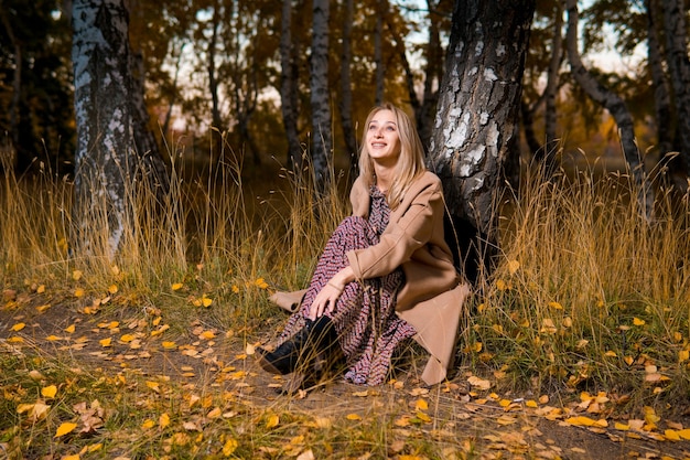 Mulher com um casaco comprido na floresta de outono