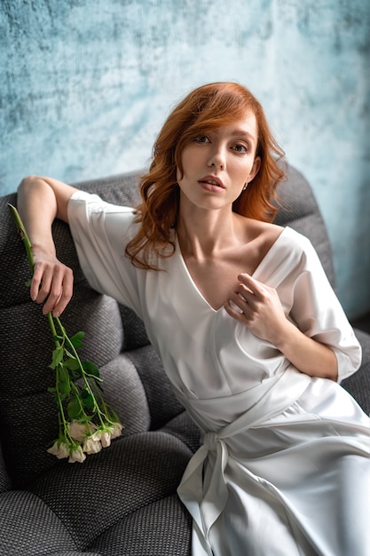Mulher com um casaco de seda branco e flores. retrato de uma mulher bonita