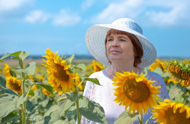 mulher com um chapéu branco parada em um campo com flores brilhantes