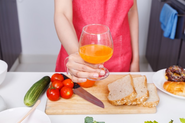 mulher com um copo de suco de laranja na cozinha