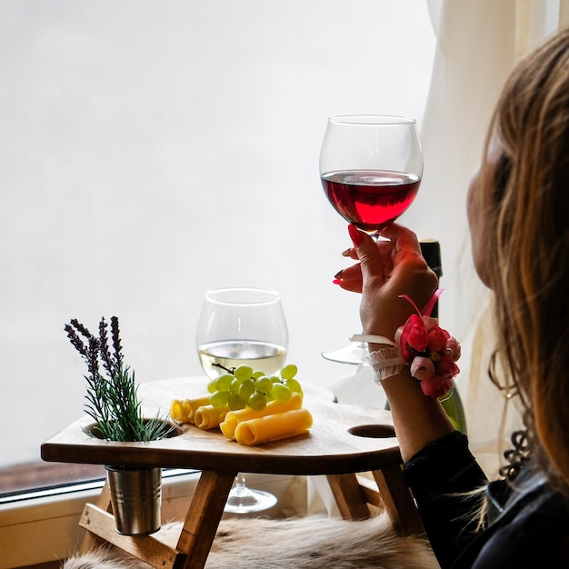 Foto mulher com um copo de vinho sentado perto da janela. dia dos namorados