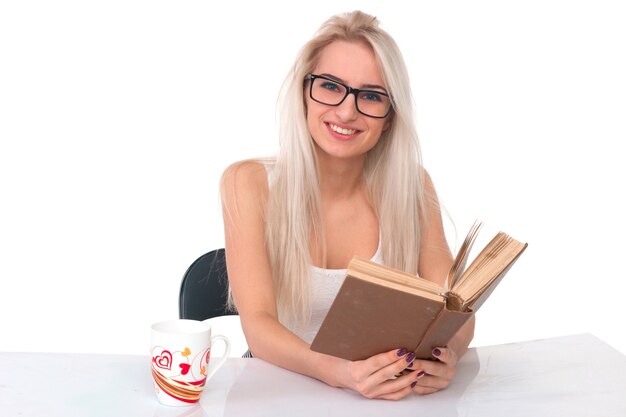 Mulher com um copo lendo um livro sobre um fundo branco