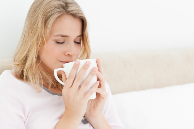 Mulher com um copo raspou o rosto, os olhos fechados, absorvendo o aroma