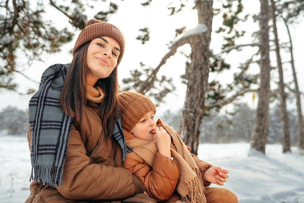 Mulher com um filho pequeno em uma caminhada de inverno na floresta de neve