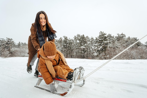 Mulher com um filho pequeno em uma caminhada de inverno na floresta de neve