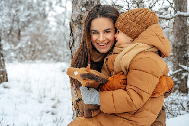 Mulher com um filho pequeno em uma caminhada de inverno na floresta de neve