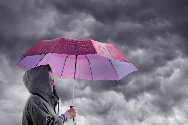 Mulher com um guarda-chuva no contexto de um céu tempestuoso escuro