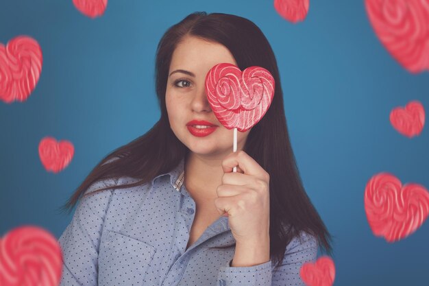 Mulher com um pirulito rosa é contra o fundo azul