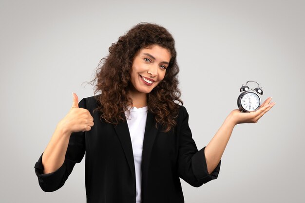 Mulher com um relógio dando polegar para o conceito de tempo