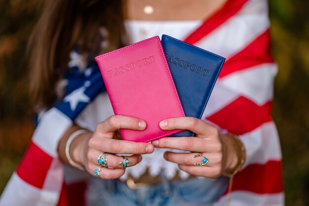 Mulher com uma bandeira americana e passaportes nas mãos dela