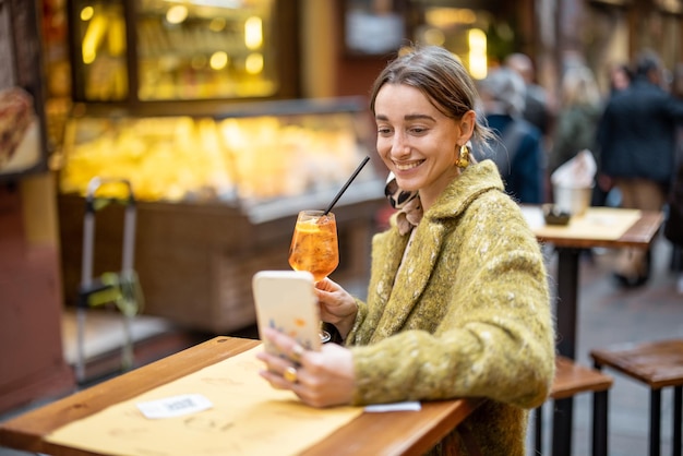 Mulher com uma bebida no bar ao ar livre na Itália