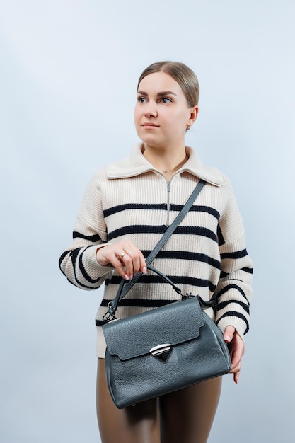 Mulher com uma bolsa de couro cinza em um fundo branco bolsa de embreagem elegante foto vertical aproximada