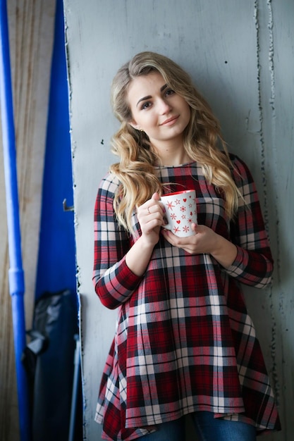 Mulher com uma camisa xadrez e uma xícara de café nas mãos