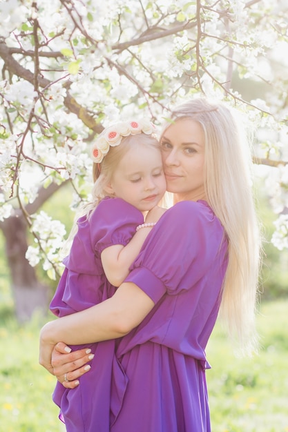 Mulher com uma filha caminhando através da maçã florescendo