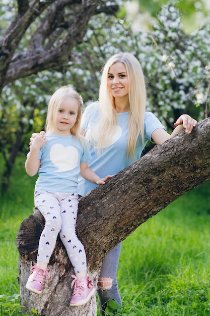 Mulher com uma filha caminhando através da maçã florescendo