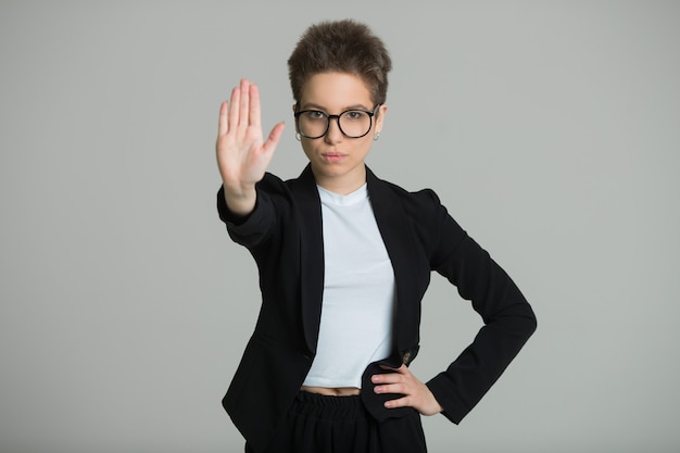 Foto mulher com uma jaqueta preta com um corte de cabelo curto e um gesto da mão