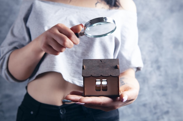 Mulher com uma lupa olha para a casa. conceito de busca em casa