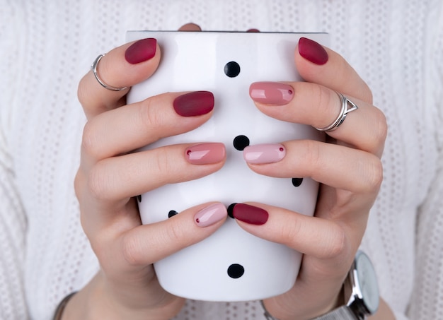 Mulher com uma manicure rosa em estilo minimalista, segurando uma xícara de café ou chá