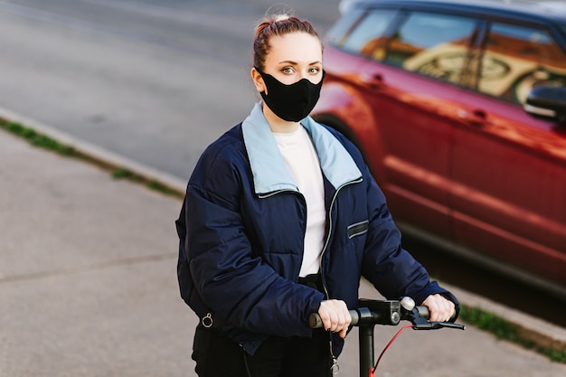 Mulher com uma máscara protetora com patinete elétrico tecnológico