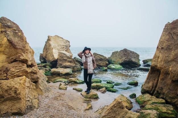 Mulher com uma mochila na costa contra um fundo de rochas contra um lindo mar