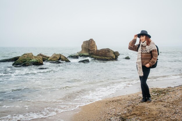 Mulher com uma mochila na costa contra um fundo de rochas contra um lindo mar