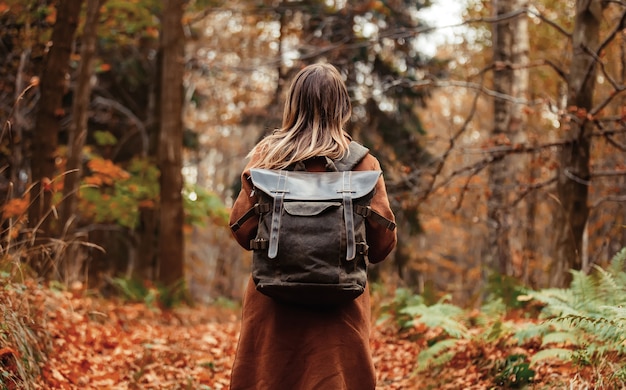 Mulher com uma mochila na floresta de outono