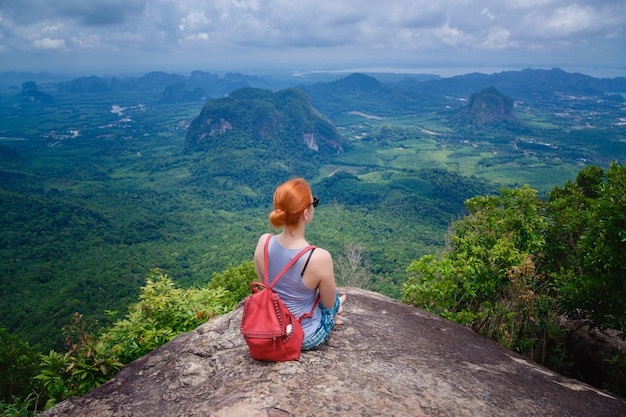 Mulher com uma mochila sentado nas pedras