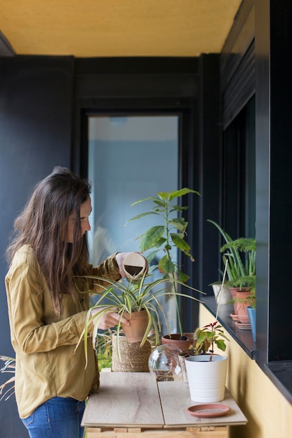 Foto mulher com uma planta em vaso em casa