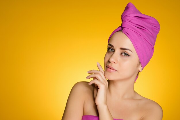 Mulher com uma toalha na cabeça após um banho em um fundo amarelo