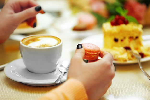 Mulher com uma xícara de café e biscoito no café