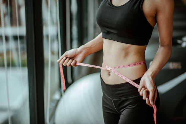 Mulher com uniforme de fitness E está usando a linha da cintura na academia.