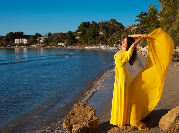 Mulher com vestido amarelo na praia.