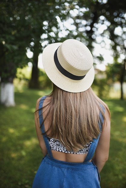 Mulher com vestido azul e chapéu branco no parque