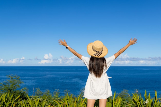 Mulher com vestido branco e desfrutar da vista do mar com o céu azul