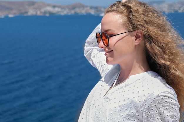 mulher com vestido branco, óculos de sol no terraço branco do resort villa hotel