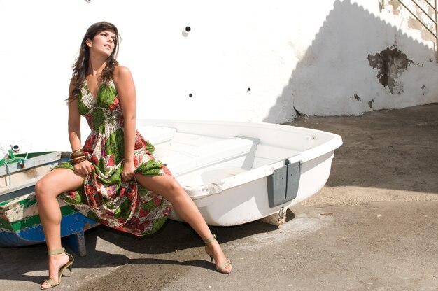 Mulher com vestido de flor em um barco na praia