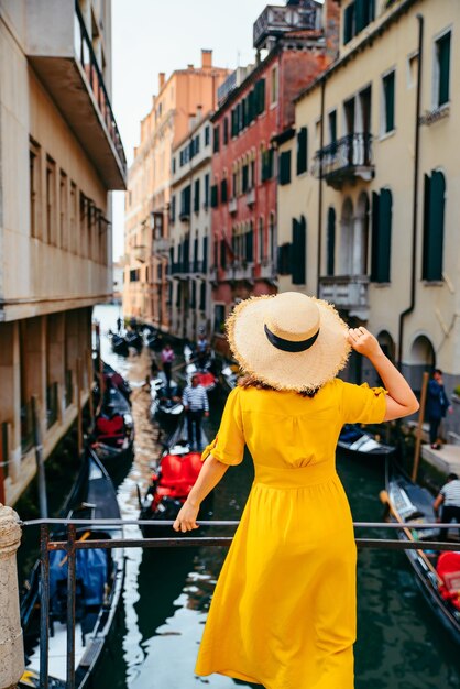 Mulher com vestido de verão amarelo na ponte com vista para o canal de veneza