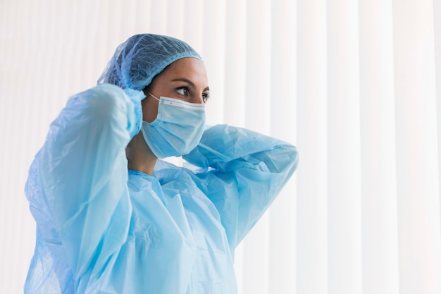 Foto mulher com visão lateral colocando uma máscara protetora