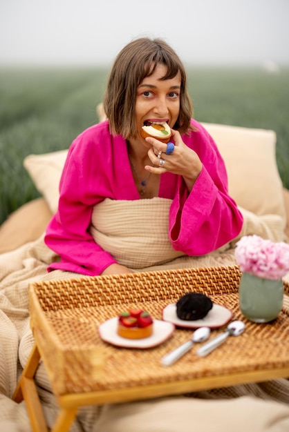 Mulher come doces enquanto acorda no campo ao ar livre