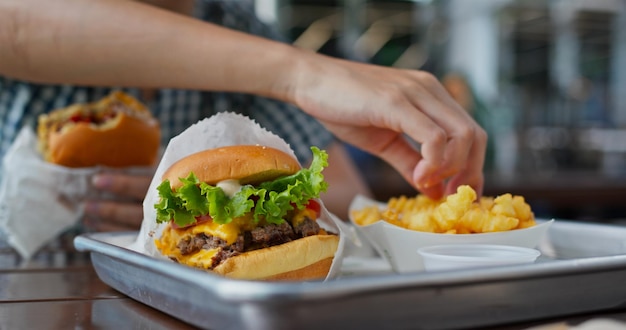 Foto mulher come hambúrguer em restaurante de fast food