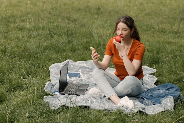 Mulher come maçã no parque