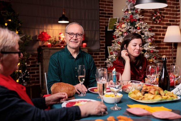 Mulher comemorando o natal com a família, sentada à mesa de jantar festiva com o pai na festa em casa. pai e filha comendo pratos de natal cozidos em casa em retrato de belo lugar decorado