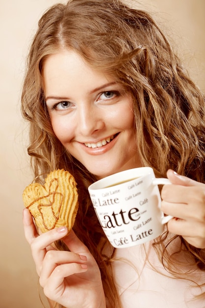 Mulher comendo biscoito e tomando café