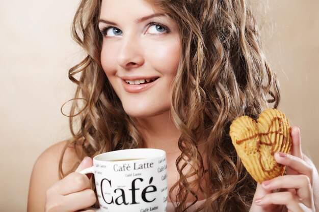 Mulher comendo biscoito e tomando café