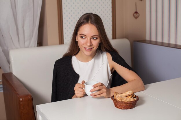 Mulher comendo biscoitos e bebendo chá quente no café